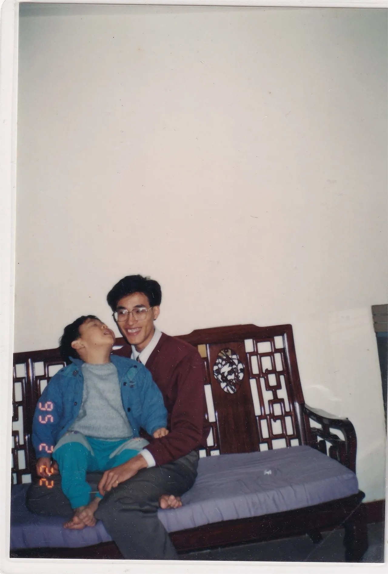 木椅上成人与幼儿合影，正面。